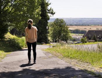 Person läuft eine Straße im Grünen entlang